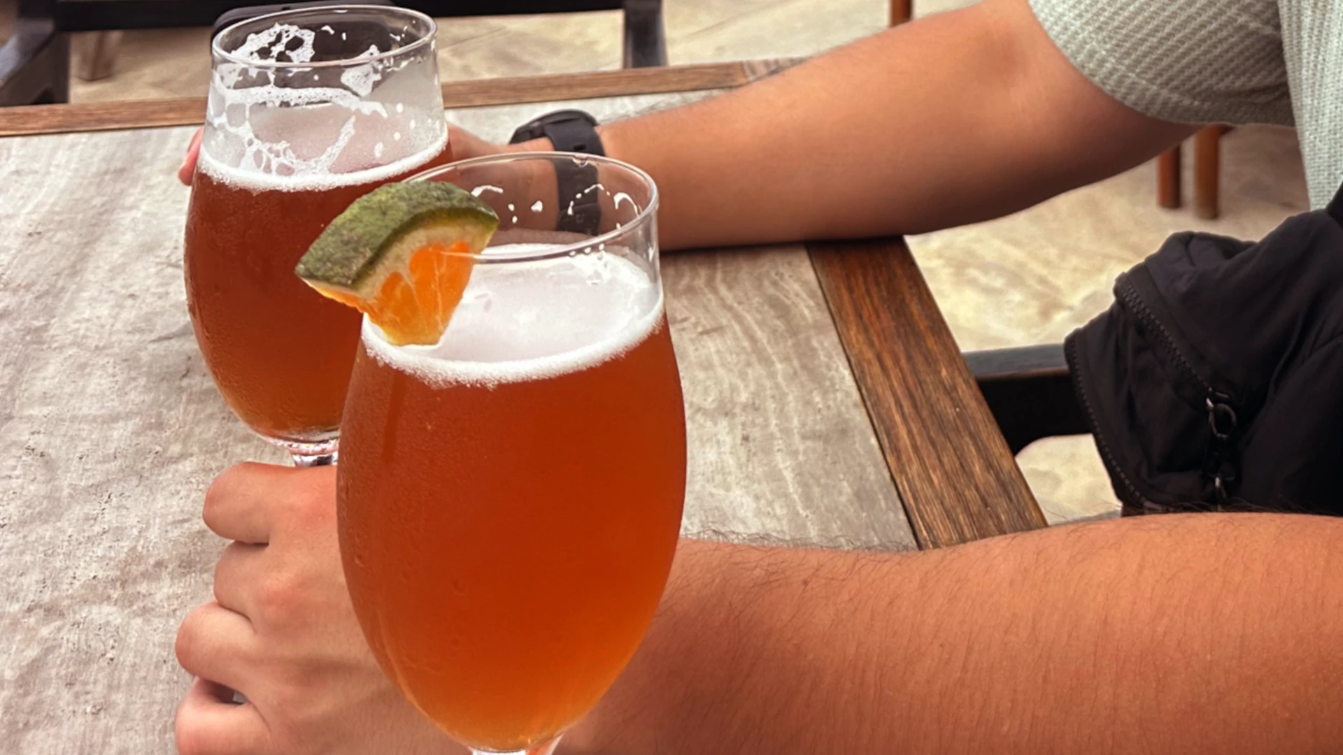 Two beers on the table, one with a wedge of grapefruit garnish