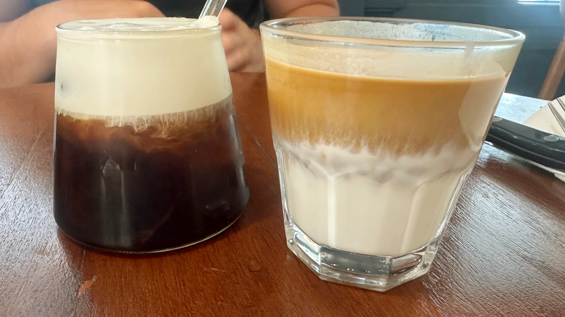 Two coffees, one with foam on top and one with milk on the bottom
