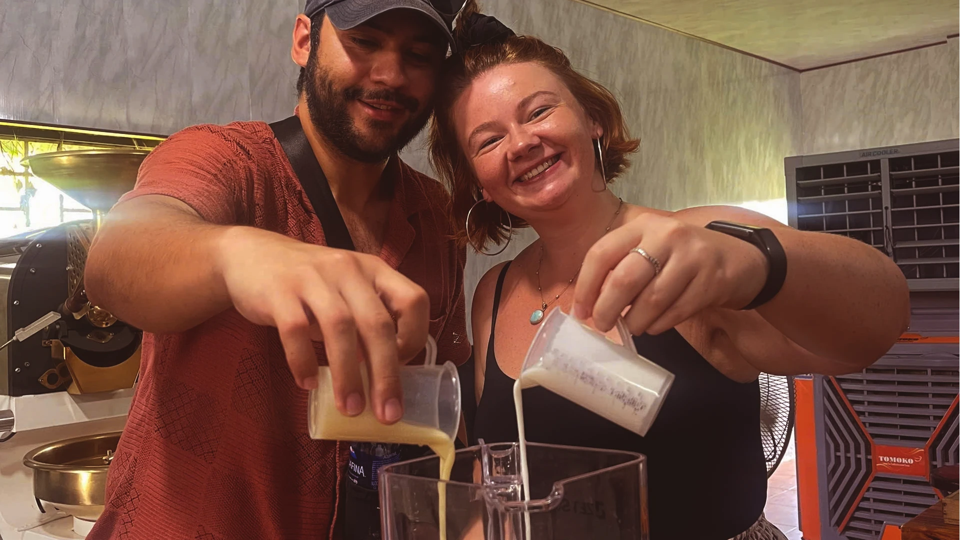Eloise and Ramiro pouring ingredients into a blender to make coconut coffee