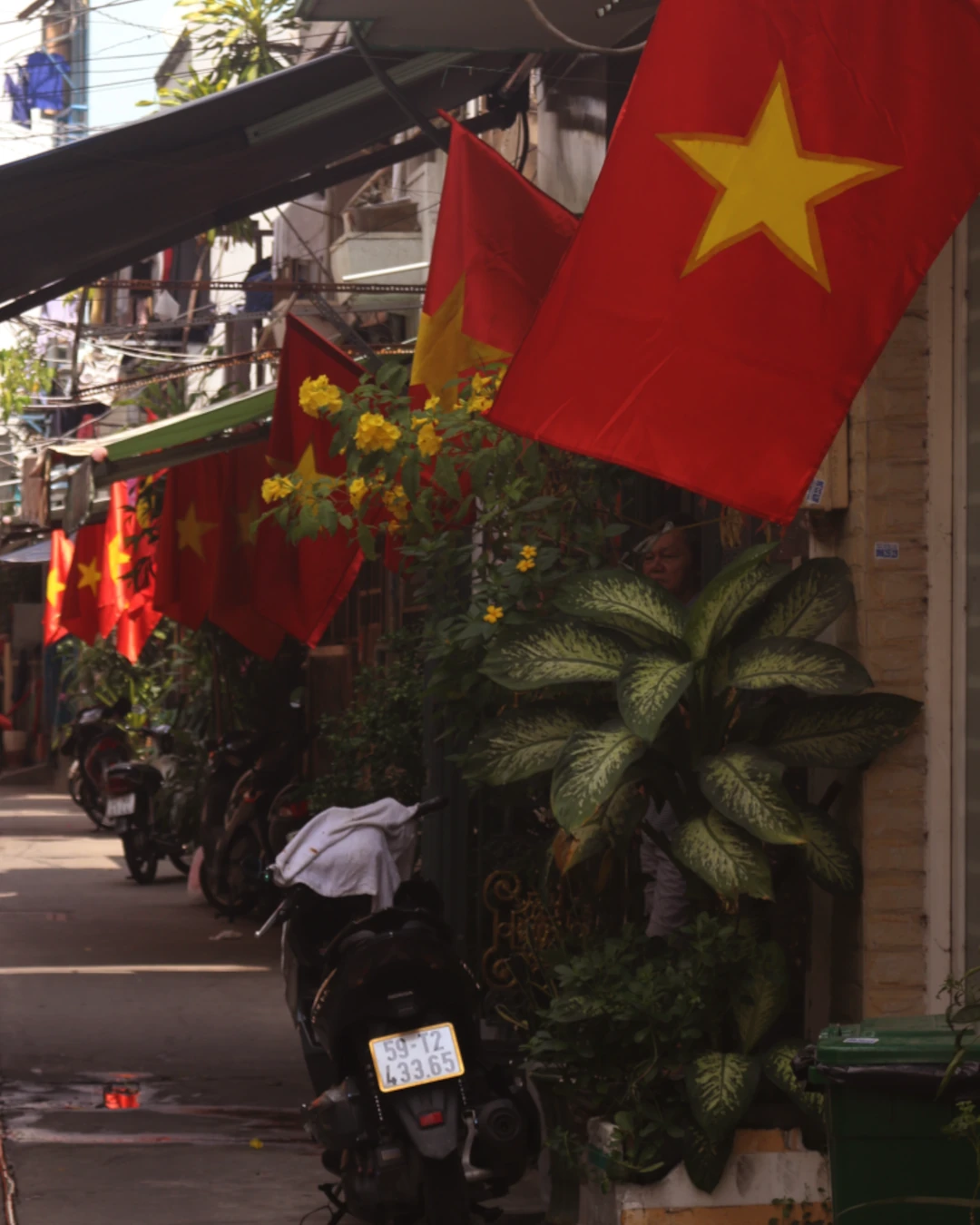 small alleyway lined with vietnameseflags and motorbikes